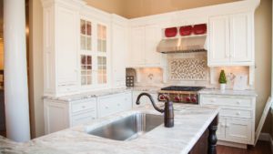 A kitchen with white cabinets and red accents.