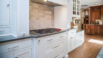A kitchen with white cabinets and tile backsplash.