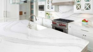 A kitchen with white marble countertops and silver appliances.