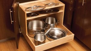 A wooden cabinet with pots and pans in it.