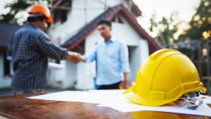A man shaking hands with another person wearing hard hat.