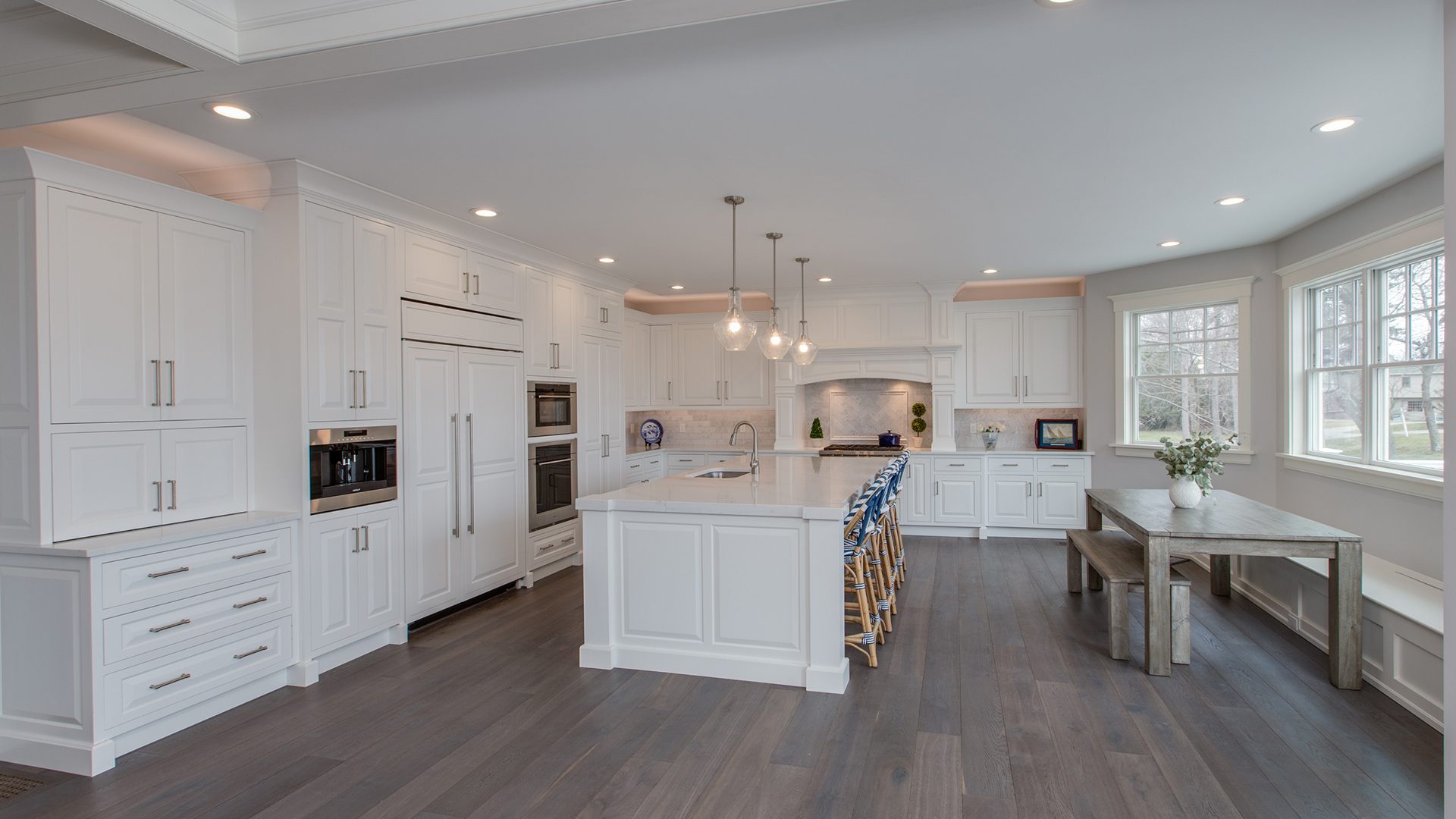 A kitchen with white cabinets and wood floors