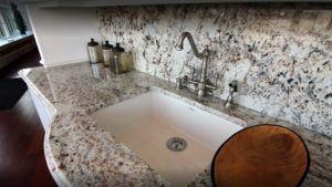 A white sink sitting under a marble counter.
