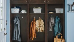 A closet with three coats of clothes hanging on the wall.