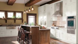 A kitchen with white cabinets and wooden island.