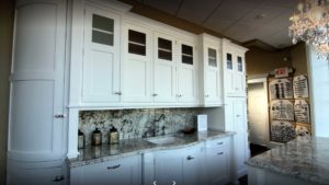 A kitchen with white cabinets and marble counter tops.