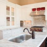 A kitchen with white cabinets and a sink.