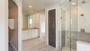 A bathroom with wood floors and white cabinets.