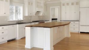 A kitchen with white cabinets and wood countertops.