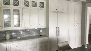 A kitchen with white cabinets and gray tile backsplash.