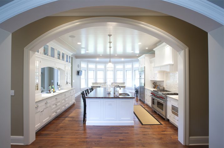 A kitchen with white cabinets and wood floors