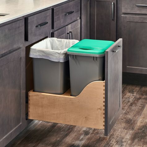 A kitchen with two trash cans in the bottom of it.