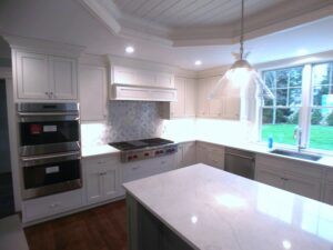 A kitchen with white cabinets and a large window.