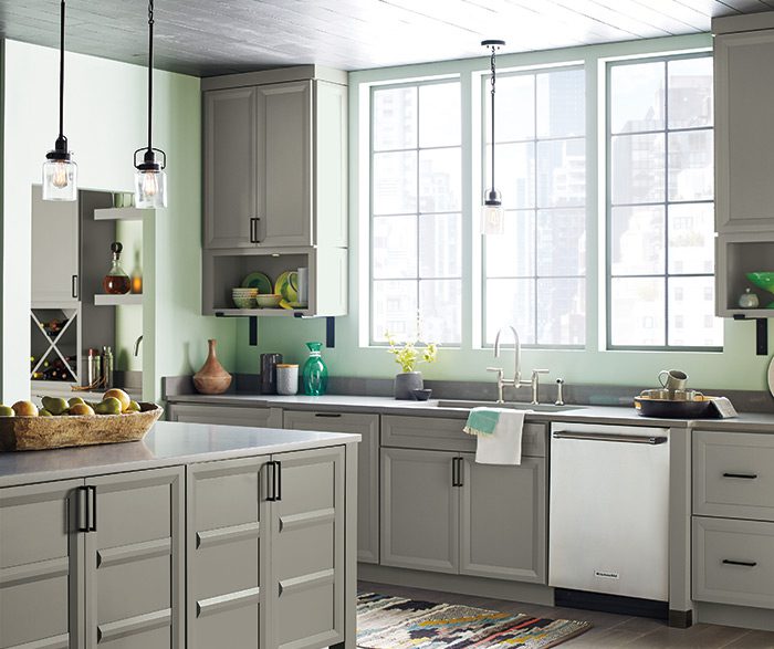 A kitchen with grey cabinets and green walls.