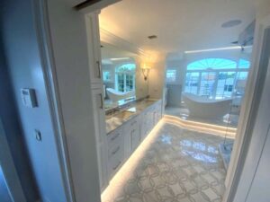 A bathroom with white cabinets and marble floors.