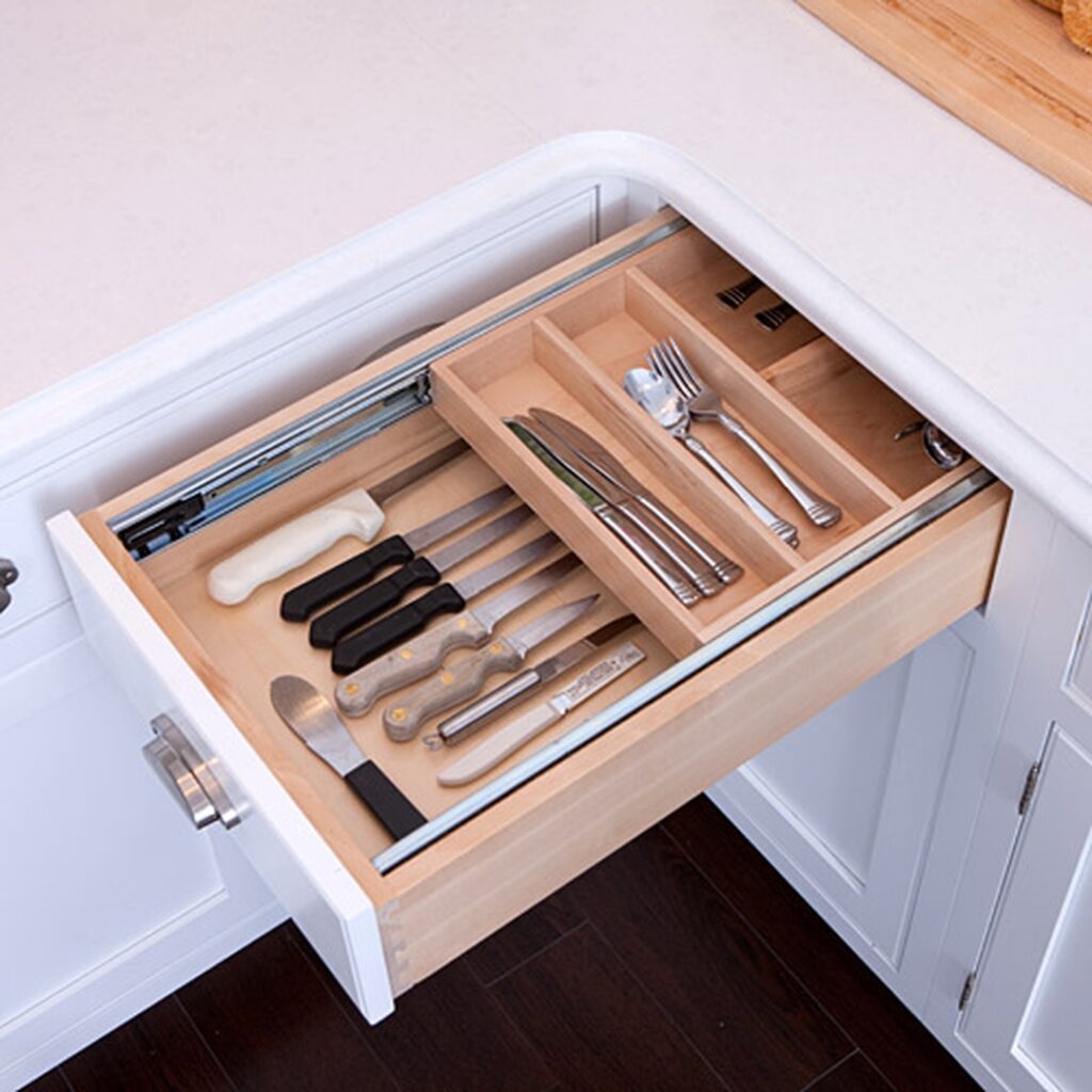 A drawer with many compartments and knives in it