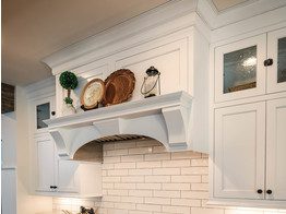 A white kitchen with a fireplace and a brick wall