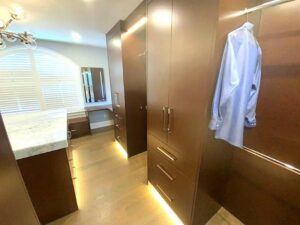 A large walk in closet with brown cabinets and drawers.
