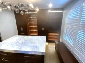 A room with dark wood cabinets and marble counter.