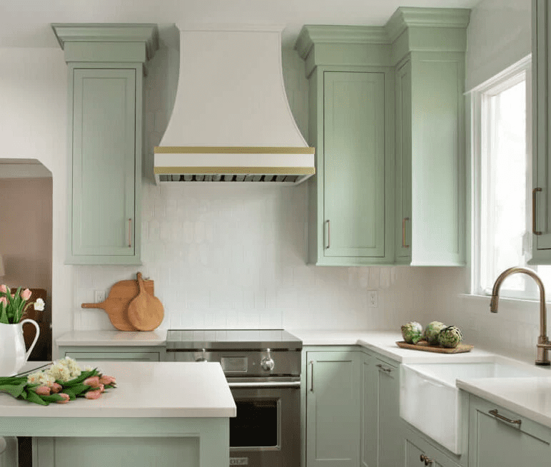 A kitchen with green cabinets and white counters.