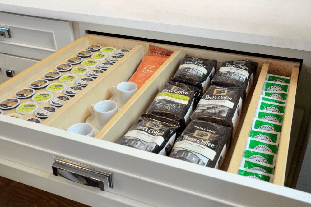 A drawer with coffee beans and cups in it.