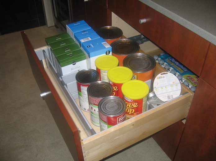 A drawer with many cans of food in it