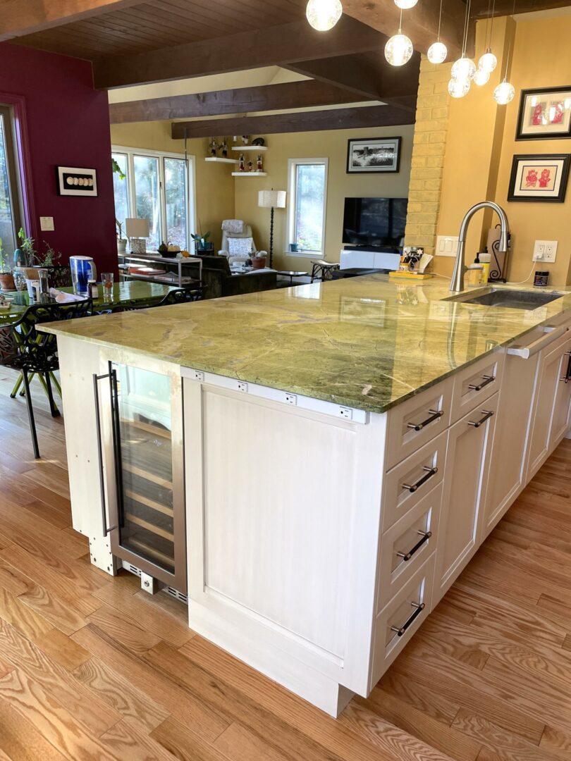 A kitchen with a large island and wine cooler.