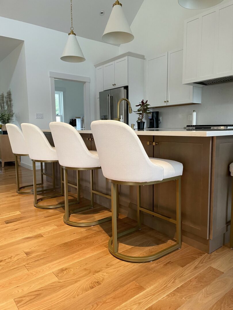 A kitchen with white chairs and wooden floors