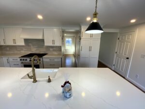 A kitchen with white counters and cabinets, and a sink.