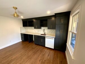 A kitchen with black cabinets and white counters.