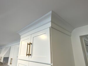 A white cabinet with gold handles and a crown molding.