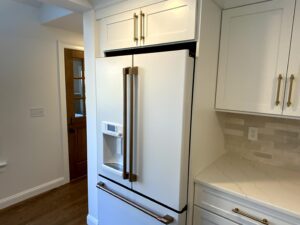 A white refrigerator with gold handles and knobs.