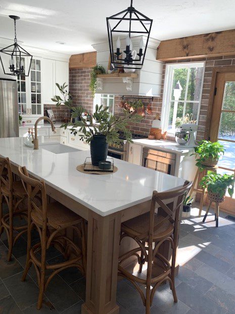 A kitchen with a large island and wooden chairs.