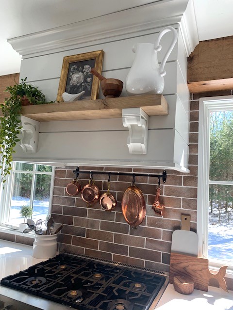 A kitchen with a brick wall and a pot rack.