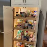 A pantry with many items in it and lights on.