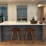 A kitchen with two stools and a sink