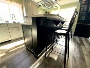 A kitchen with wooden floors and black cabinets.