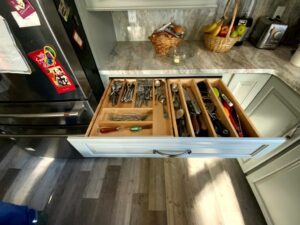 A kitchen drawer with many compartments and tools.