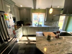 A kitchen with grey cabinets and marble counter tops.