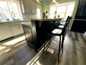 A kitchen with black and white cabinets, a bar stools.