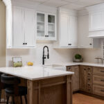 A kitchen with white cabinets and brown wood floors.