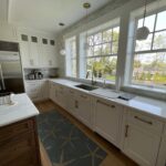A kitchen with white cabinets and wooden floors.