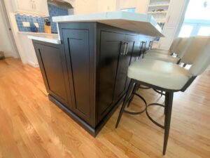 Modern kitchen island with bar stools in a home with hardwood flooring.