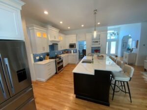 Modern kitchen interior with white cabinetry, stainless steel appliances, and a center island with seating.