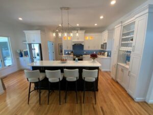 A bright, modern kitchen with white cabinetry, a central island with seating, and blue backsplash tiles.