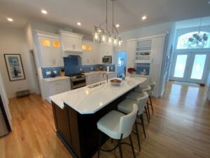 Modern kitchen with white cabinetry, blue tile backsplash, and a central island with seating.