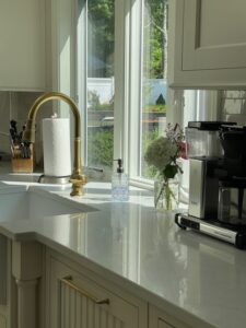White kitchen counter with coffee maker and faucet.