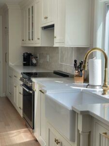 White kitchen with farmhouse sink and gold hardware.