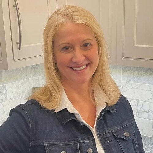 winn-headshot A woman in a blue jean jacket standing next to a counter.
